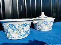 Photo showing both ceramic serving bowls with detailed Lotte design featuring blue and green illustrated characters and floral motifs. One bowl has a lid, the other does not.