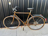 Side profile of the full Bianchi road bicycle showing brown frame, tires, fenders, saddle, handle bars, and pedals.