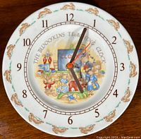 Top-down view of the round Royal Doulton Bunnykins teaching plate clock showing the clock face with bunny illustrations and hour numerals.
