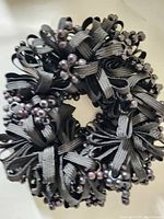 Full view of black hair band showing loops of ribbon and bead clusters.