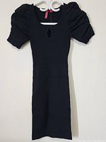 Full view of black women's long dress with puff sleeves and keyhole neckline, hanging on hanger.