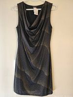 Front view of dark sleeveless dress showing draped neckline and dot swirl pattern