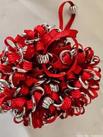 Close-up image of top view of red fabric hair band with silver beads scattered throughout the loops.