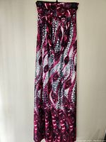 Full view of pink peacock feather and leopard print long dress hanging on hanger
