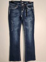 Front view of dark blue denim women's pants size 7 showing distressed detailing, stitching and front pockets.