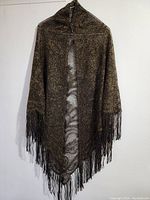 Full view of the silk shawl hanging, showing metallic mink coloration, fine weave, and fringe tassels along edges.