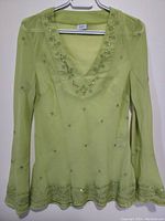 Front view of the lime green women's decorative top displaying the overall design, long sleeves, and shape.