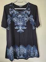 Full front view of the navy top showing the floral and ornamental design of light blue on dark navy fabric with elbow-length sleeves.