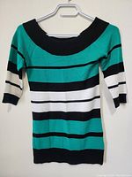 Full front view of Le Chateau women's striped top hanging on white hanger showing wide black neckline, 3/4 sleeves, and horizontal stripes in teal, white, black, and thin black lines.