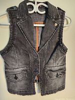 Front view of new MOTO women's denim vest jacket in size XS, showing acid wash fabric, buttoned flap pockets, and collar detail.