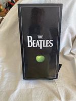 Front of black slipcase featuring The Beatles logo and green apple