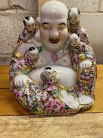 Front view of the vintage Asian Laughing Buddha statue showing the Buddha surrounded by five little Buddha babies, all decorated with colorful floral patterns and gold accents.