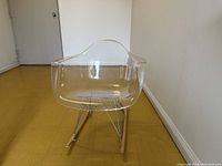 Front view of clear acrylic shell seat and wooden rockers with chrome wire supports.