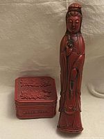 Amber resin Guan Yin statue standing next to red cinnabar style trinket box, showing scale and detailing.