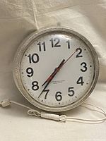 Front view of the Westclox vintage school electric wall clock showing white face with black numbers and hands, red second hand, and electric cord.