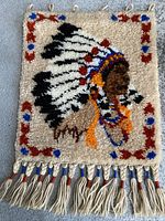 Front view of vintage wool tapestry wall hanging showing Indian Chief bust and feathered headdress with bottom fringe tassels.