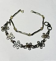 First photo shows bracelet with oval and circular linked shapes combined with flower motifs, polished silver finish, simple clasp.