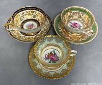 Three Paragon teacup and saucer sets on gray surface, assorted border colors