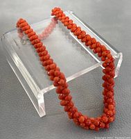 Detailed close-up of the coral necklace showing bead texture and clasp.