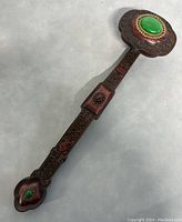 Photo showing the entire ruyi staff with large green stone and smaller red stone inlays, and carved wood body.
