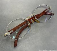 Folded round-frame eyeglasses showing silver rims and brown temples