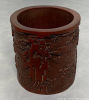 Front view showing detailed hand carved landscape and architectural scenes on bamboo vase.