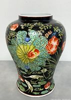 Full view of the vase showing the bulbous shape and colorful hand-painted floral and bird motifs on black background.