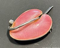 Close-up photo of the brooch back showing pin and silver stem against a black background.