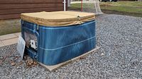 Side view of closed hot tub showing blue swirl shell and tan cover.