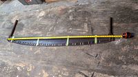 Top down view of the entire saw with a tape measure showing about 66 inches length, surface worn workbench background.