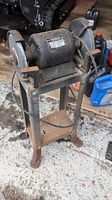 Front angle of the Craftsman bench grinder on metal stand with visible rust and wear.