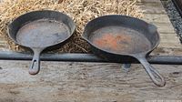 Photo of the top surfaces of the two cast iron fry pans showing rust and dirt.