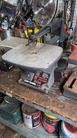 Full view of Craftsman 16-inch scroll saw sitting on a workbench with surrounding tools and supplies