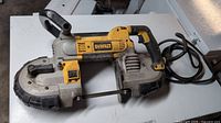 Side view of DeWalt portable band saw showing housing, handle, trigger and cord.