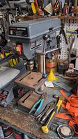 Side view of the Sears Craftsman 8" drill press on workbench with accompanying hand tools.