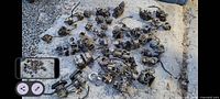 Large group of about 20+ used boat carburetors and related parts laid on a snowy outdoor surface, showing wear and corrosion.