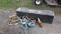 Photo of closed aluminum diamond plate toolbox and assorted ratchet straps and chains on ground