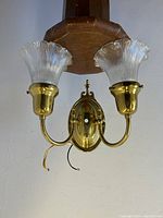 Top view showing brass twin arm wall sconce with clear fluted glass shades and oval back plate, wired and ready to hang.