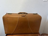 Full exterior view of brown vintage leather suitcase showing front and handle.