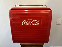 Front view indoors on stand showing ribbed panel and white “Drink Coca-Cola” logo.