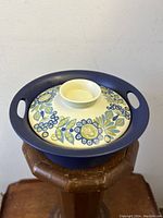 Blue ringed, handled stoneware casserole with a floral-patterned lid.