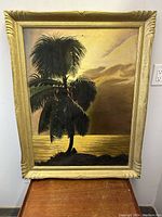 Full view of large palm tree sunset oil painting mounted in decorative wood frame, showing overall colors and condition.