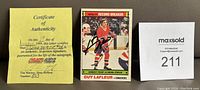 Photo shows the autographed Guy Lafleur hockey card between Certificate of Authenticity and lot number card