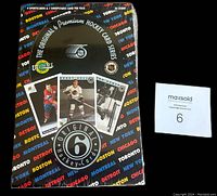 Front view of sealed box showing hockey player card images and team city names on packaging