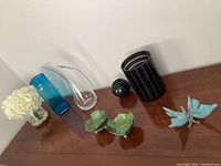 Overview of eight decorative glass table items on a wooden surface against white wall