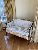 Front angled view of the love seat showing wooden frame and striped upholstery