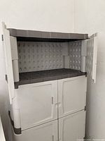 Grey Rubbermaid storage cabinet showing upper shelves with doors open, highlighting storage space and interior design.