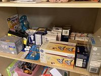 Photo showing various boxed light bulbs with labels of wattage and brands including GE and Satco.