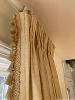 Close up photo of a yellow drape panel showing handmade tinted pleated top and decorative tassel fringe trim along edge.