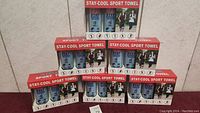 Six boxed Stay Cool Sport Towel sets stacked for sale, each box containing two towels.